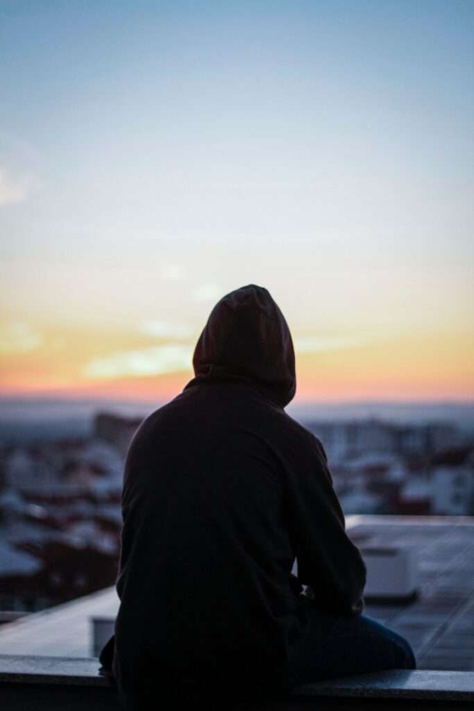 Persona solitaria de espaldas mirando al amanecer y la ciudad.